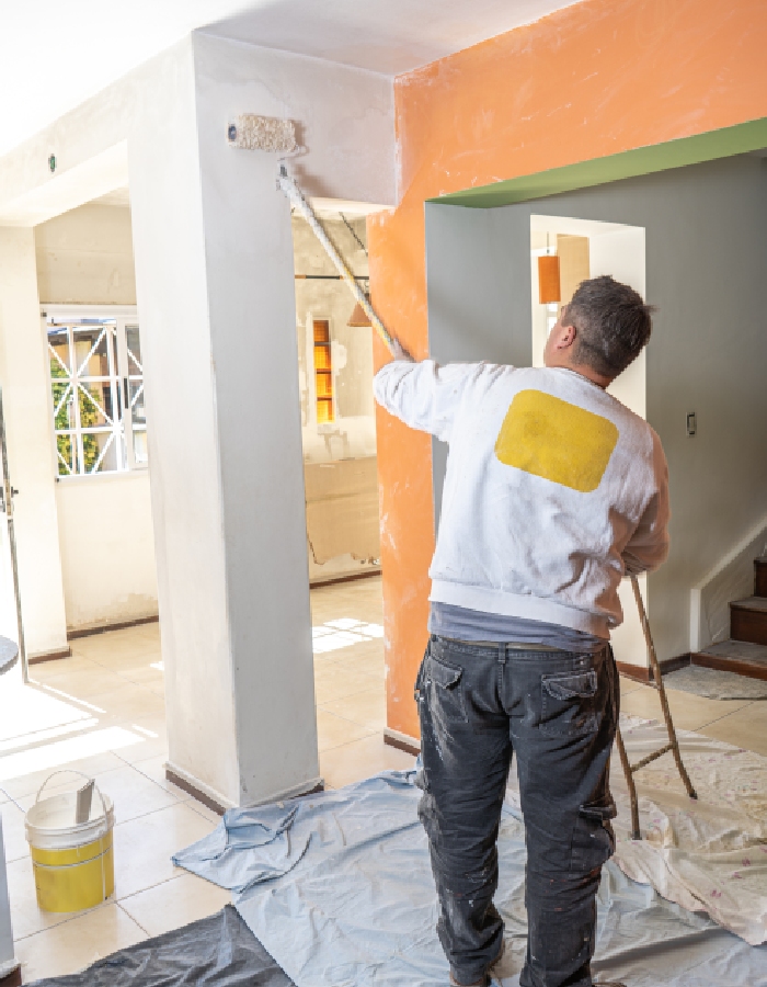 Artisan appliquant de la peinture au rouleau sur un mur intérieur.